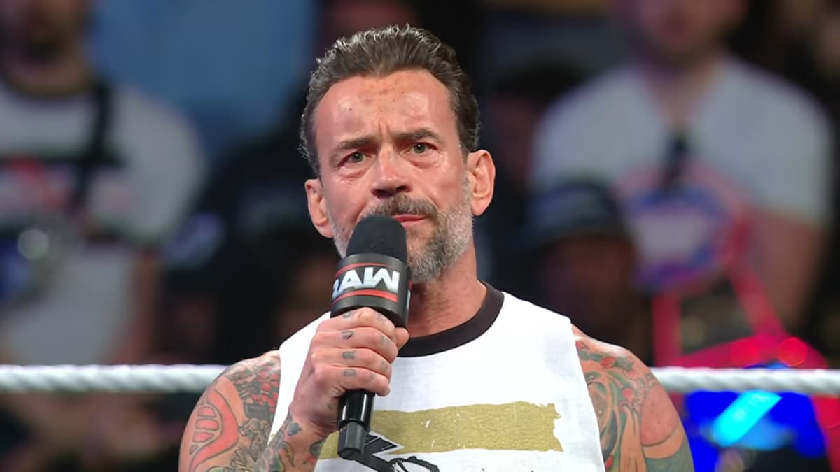 CM Punk holding a Raw microphone while wearing a white vest on WWE Raw