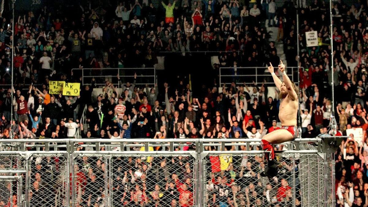 Daniel Bryan hitting on top of a steel cage leading the crowd in YES! chants