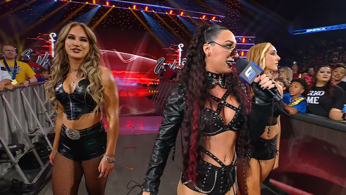 Fatal Influence walking to the ring while Jacy Jayne, in the middle, cuts a promo