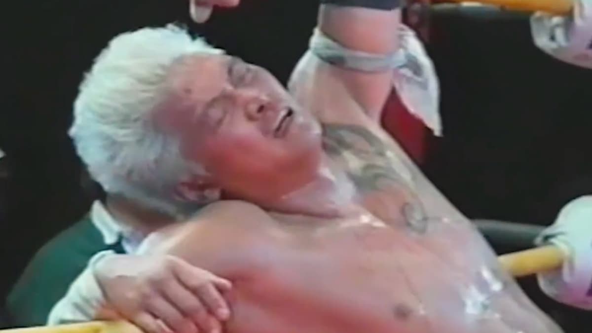 An unmasked Hayabusa lying against the ropes