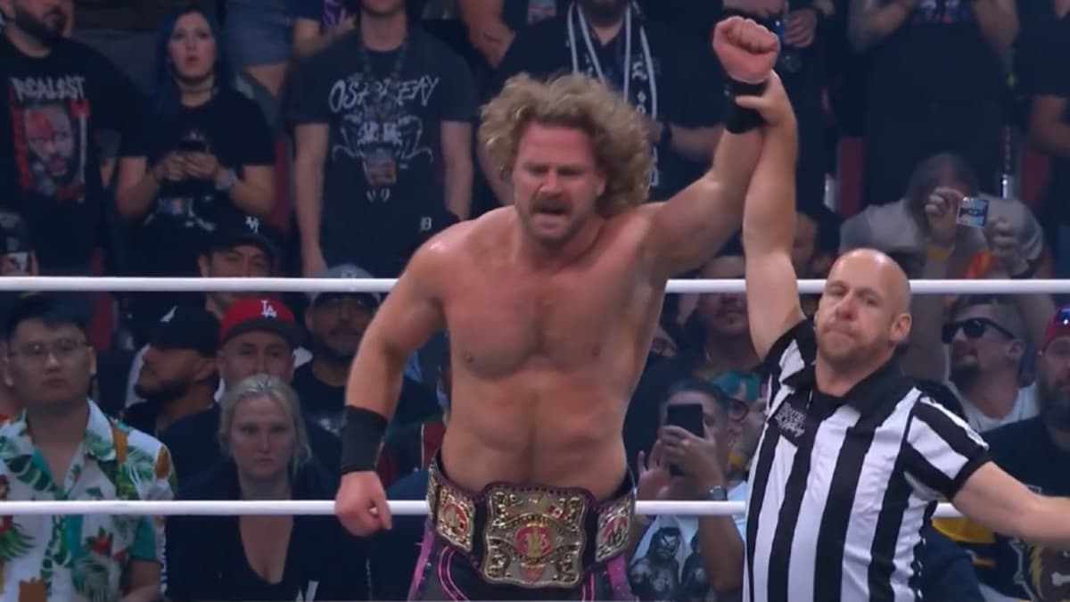 Hangman Page has his hand raised by the referee inside an AEW ring with a championship belt around his waist