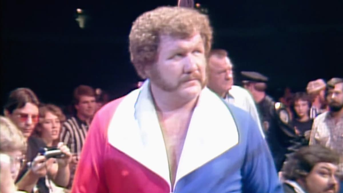 Harley Race making his entrance with mutton chops and a red and blue coat at Starrcade 1983