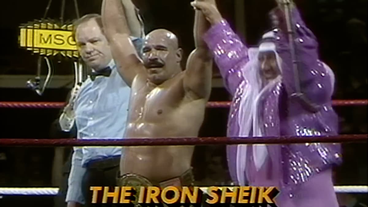 Iron Sheik with his arm raised alongside Freddie Blassie