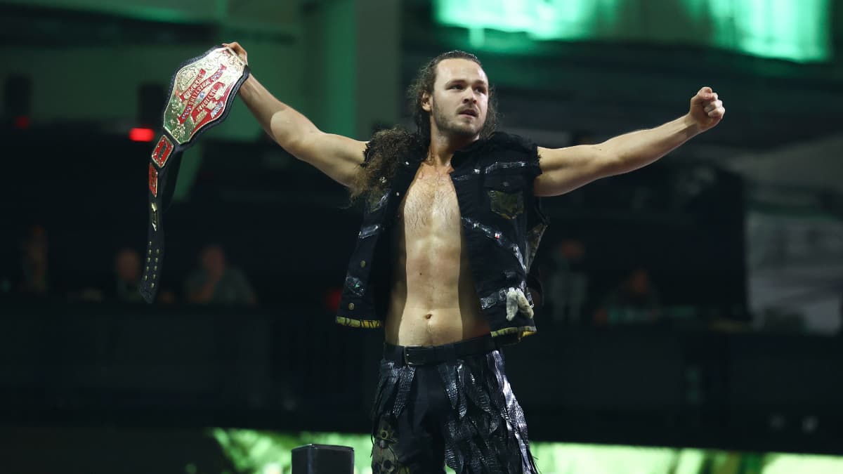 Jack Perry standing on a turnbuckle holding up the AEW National Championship