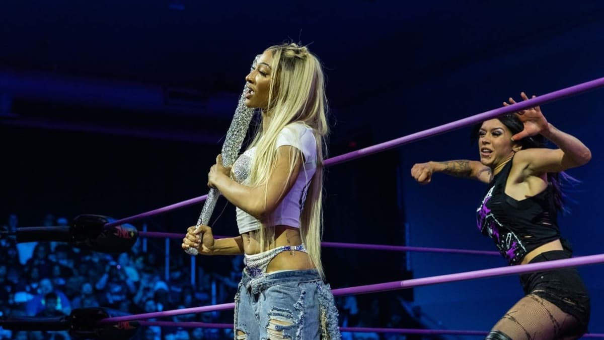 Mara Sade on the apron with Elayna Black about to attack her from behind
