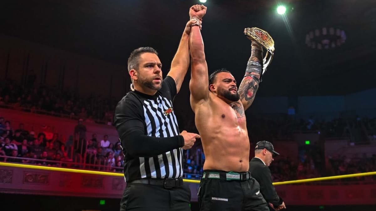 Mike Santana holding the TNA World Title with his arm raised by a TNA referee