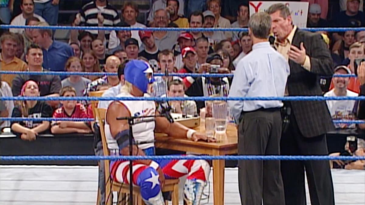 Mr America undergoing a lie detector in a WWE ring as Vince McMahon angrily speaks to the lie detectorist