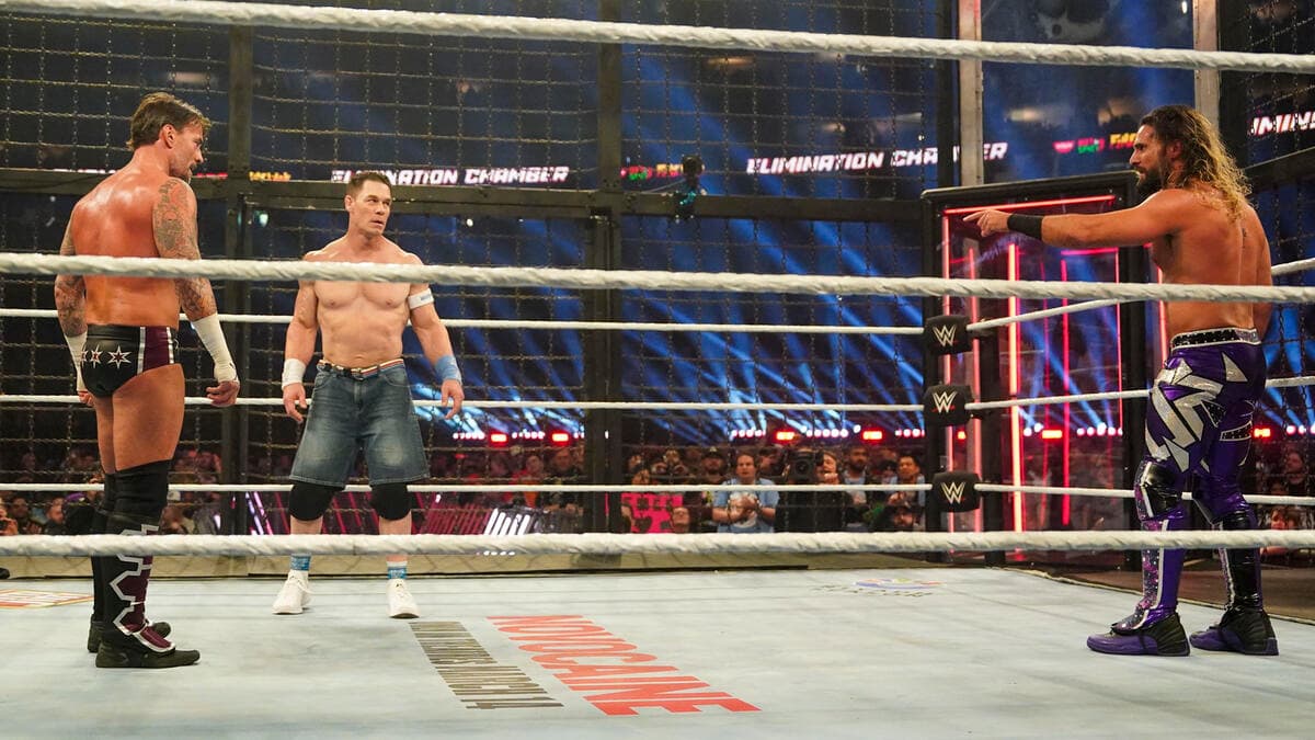 Seth Rollins, John Cena, and CM Punk looking across the ring at each other inside the Elimination Chamber