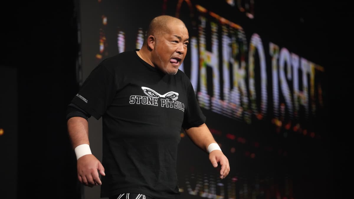 Tomohiro Ishii licking his lips as he marches to the ring in a black t-shirt