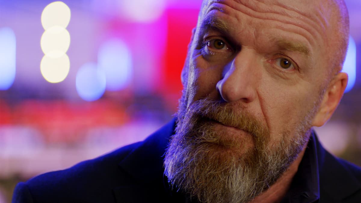 Triple H on WWE: Real in a black suit with bald head and greying beard