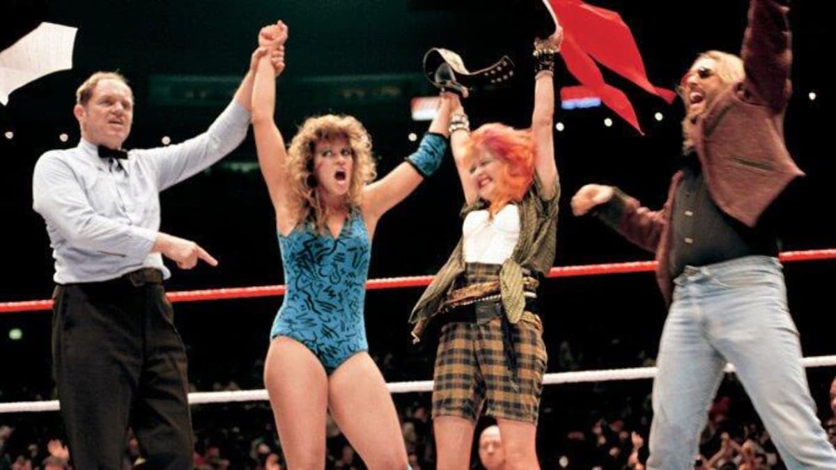 Wendi Richter and Cyndi Lauper with their arms raised celebrating at WWE WrestleMania I
