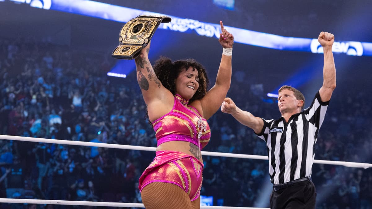 Willow Nightingale holding up the AEW Women's World Title with the referee standing to her right pointing at her