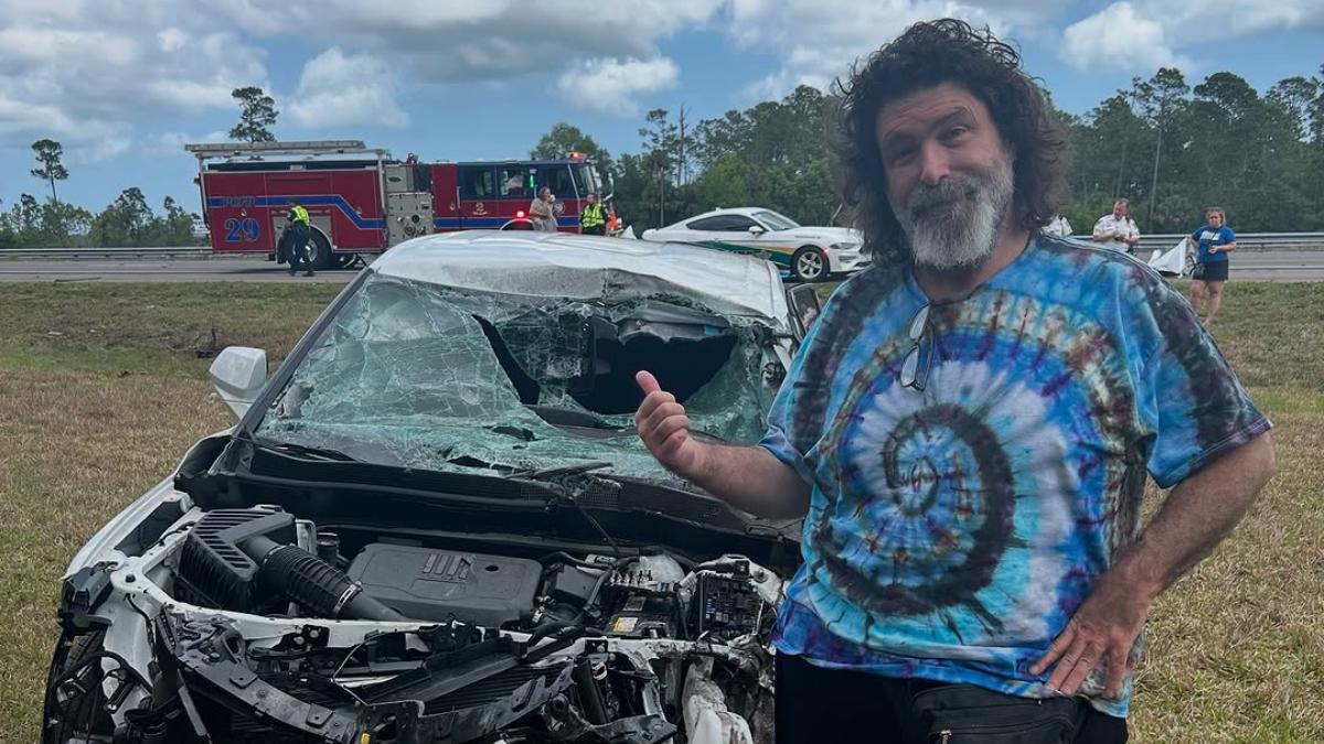 Mick Foley next to a wrecked car