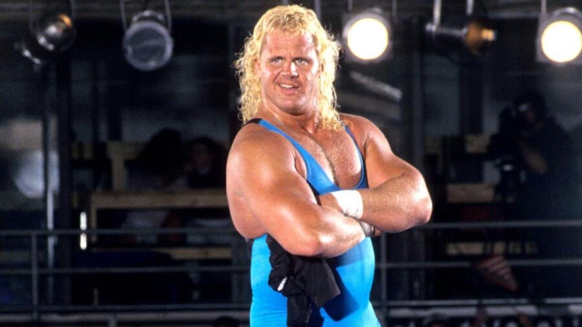 Mr. Perfect with his arms folded wearing a blue singlet