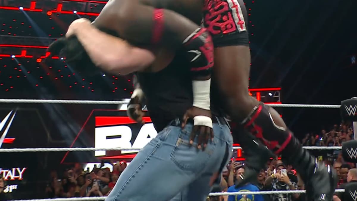 Brock Lesnar holding up Oba Femi for an F5 with split jeans
