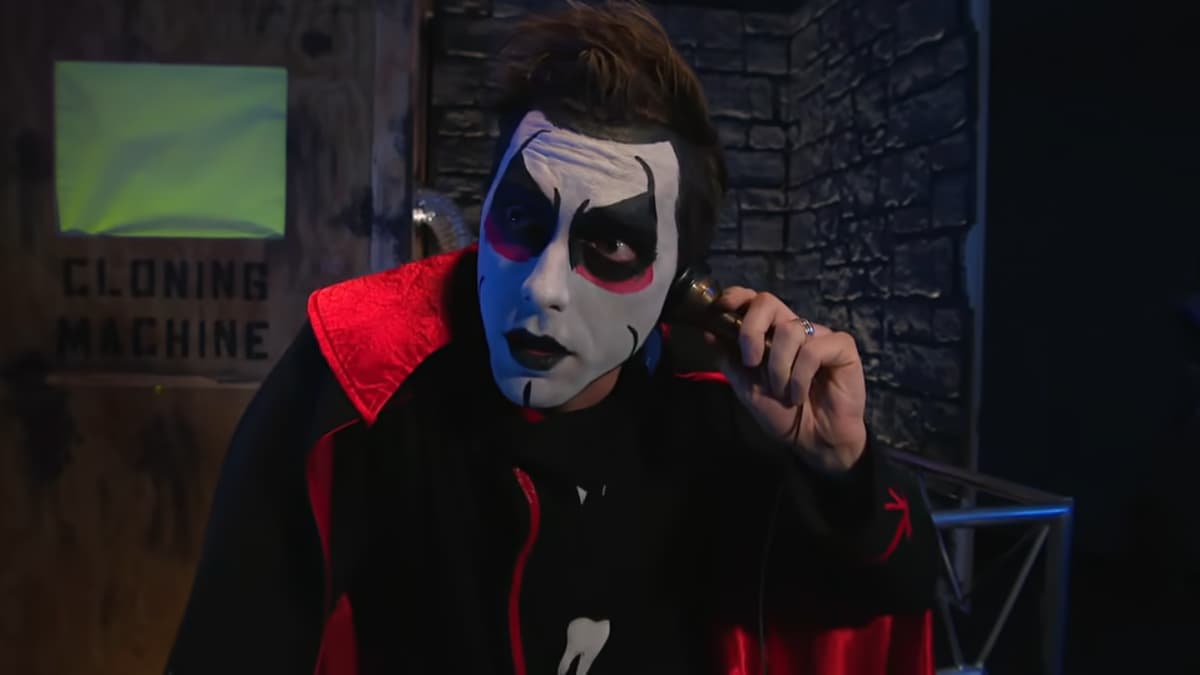 Danhausen holding an old phone to his ear while standing in front of a cloning machine