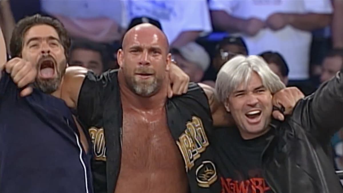 Goldberg with his shoulders over a celebrating Eric Bischoff and Vince Russo at WCW Great American Bash 2000