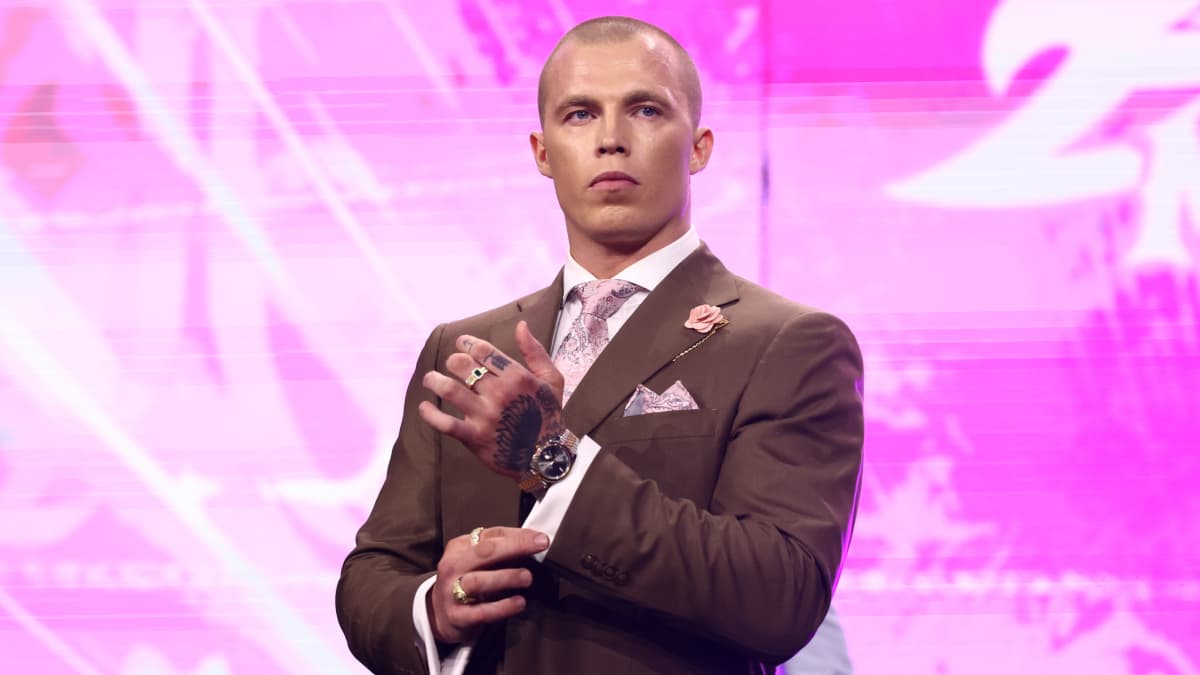 Kyle Fletcher adjusting his cuff while wearing a brown suit
