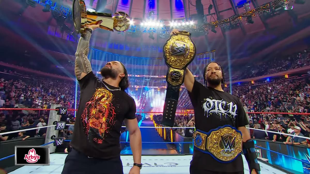 Roman Reigns holding up the NBA trophy while Jalen Brunson holds up the WWE World Heavyweight Title