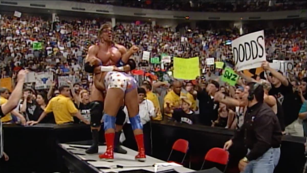 Triple H with Kurt Angle ready for a pedigree on an announce table at WWE SummerSlam 2000