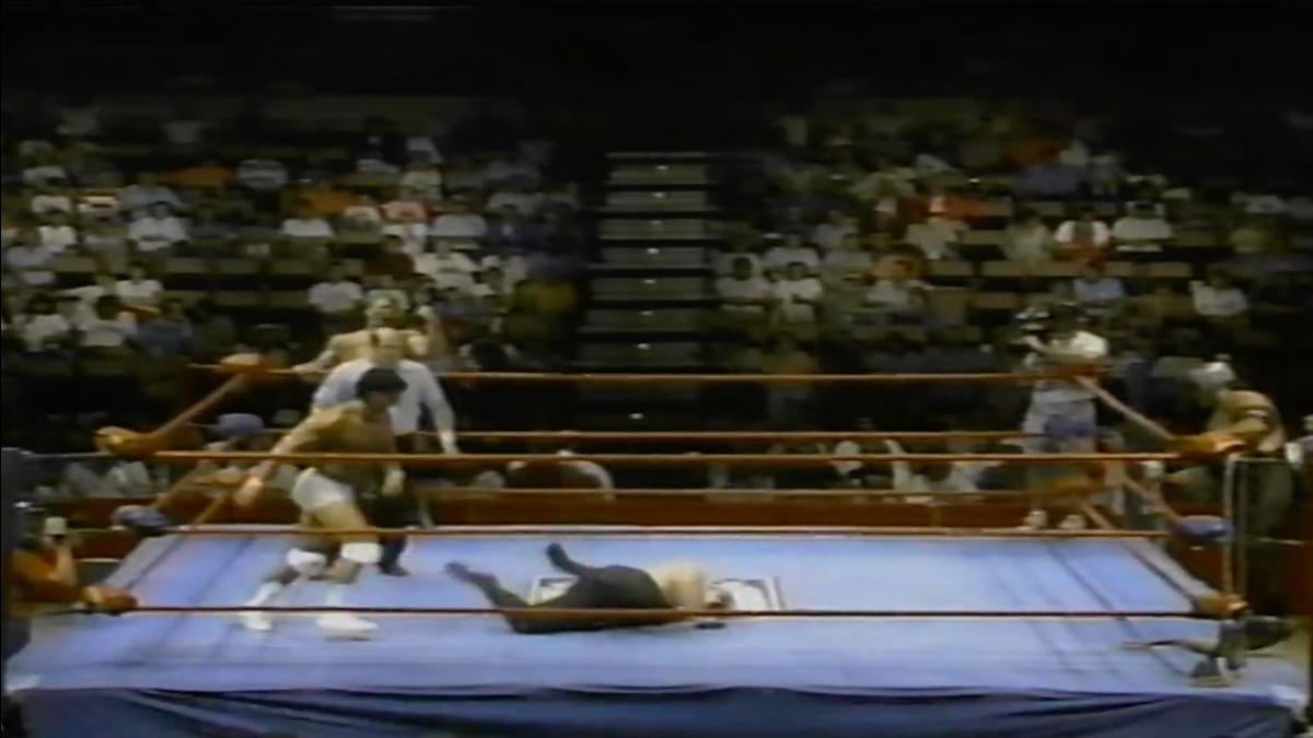 A wrestler down in the ring surrounded by empty seats