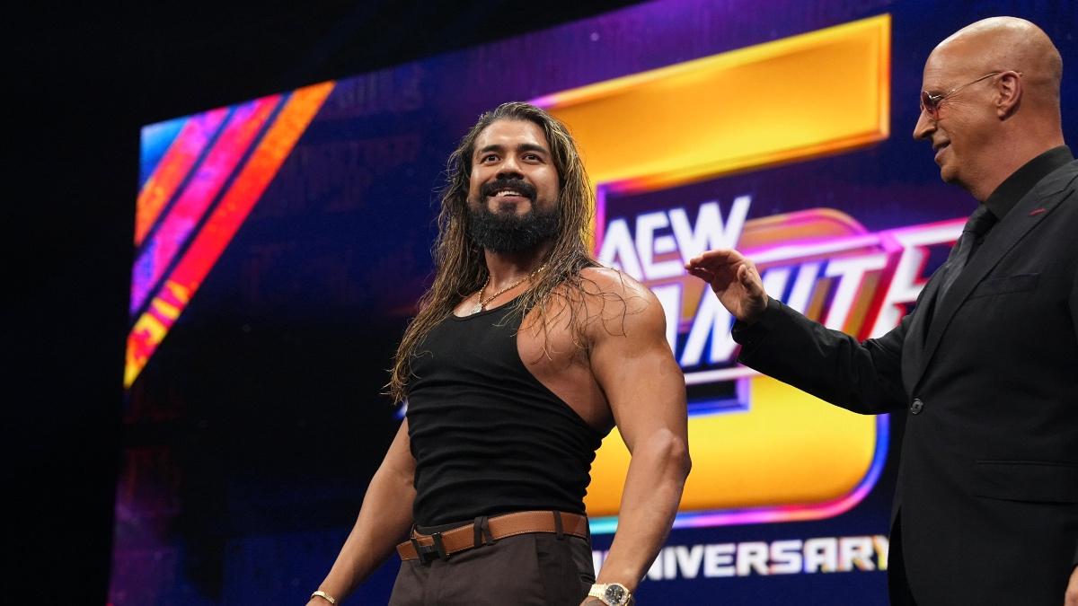 Andrade El Idolo smiling in a black vest standing alongside Don Callis
