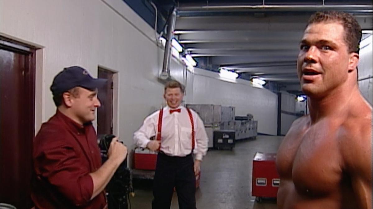 Bob Backlund walking away from an extra as Kurt Angle looks away annoyed on WWE Raw