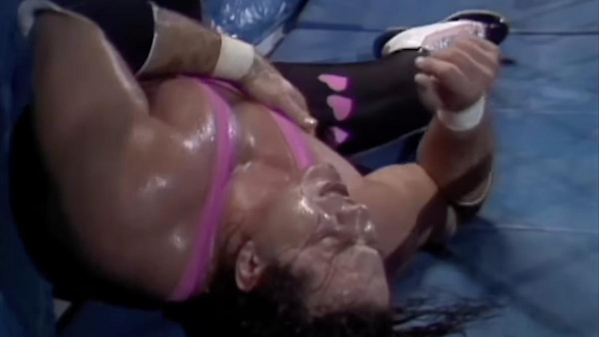 Bret Hart lying down outside of the ring holding his sternum