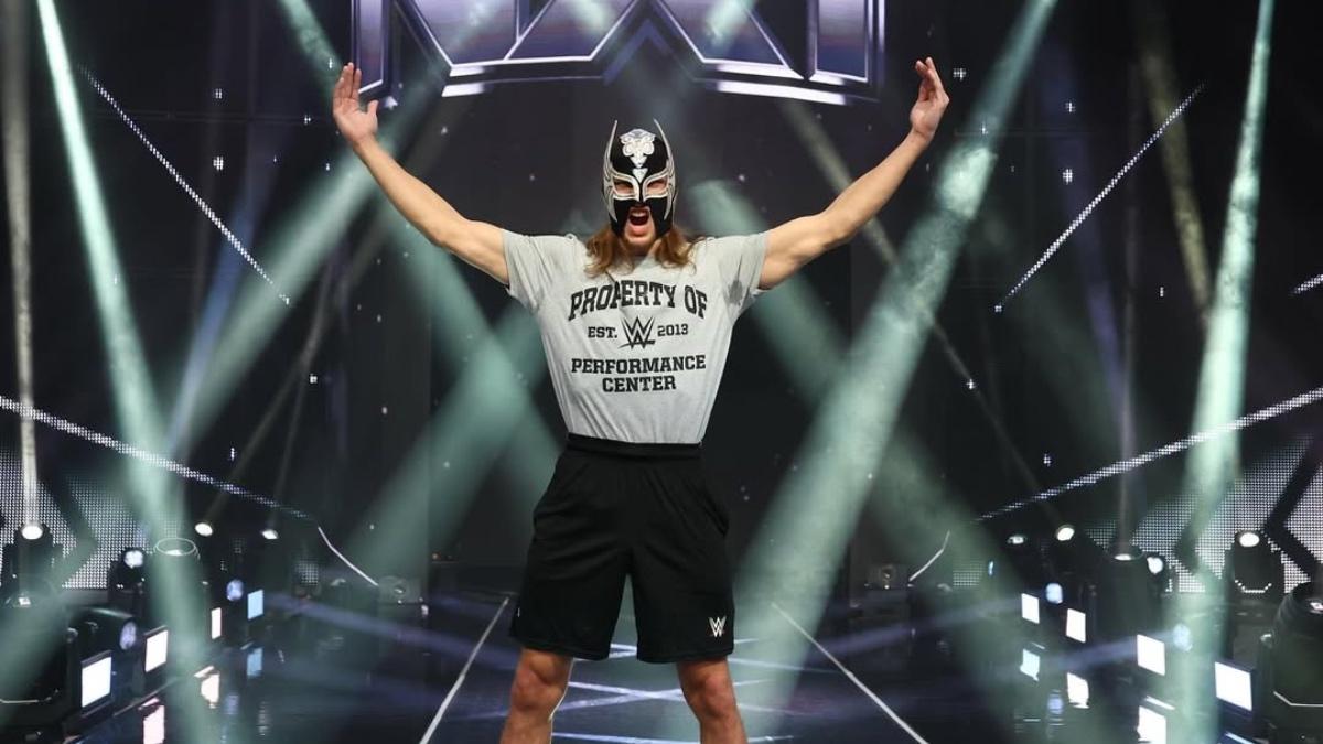 Elio LeFleur wearing a WWE Performance Center t-shirt in front of NXT logo