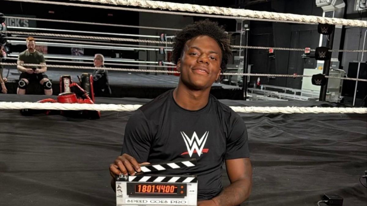 IShowSpeed sitting on a ring apron wearing a WWE t-shirt