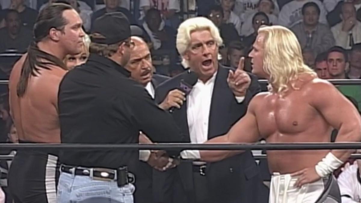 Jeff Jarrett shaking Steve McMichael's hand as Ric Flair speaks to him