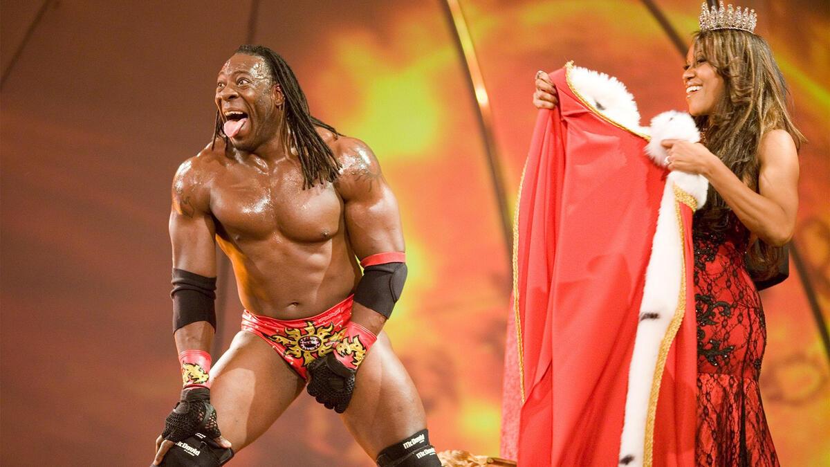 King Booker laughing while Queen Sharmell holds his cape
