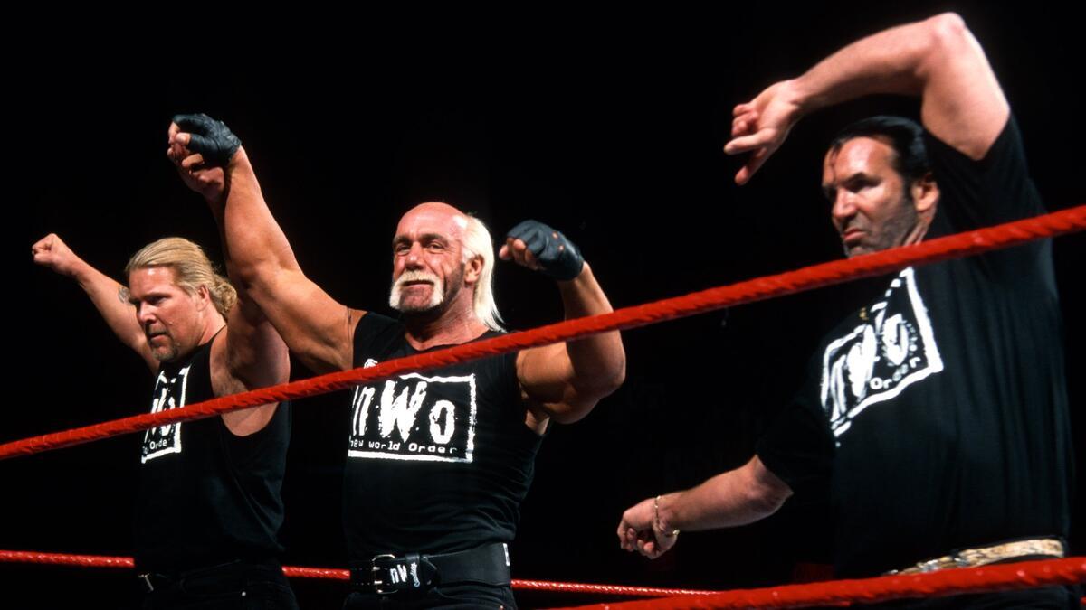 The NWO celebrating on WWE Raw with Kevin Nash raising Hollywood Hogan's arm as Scott Hall points at Hogan