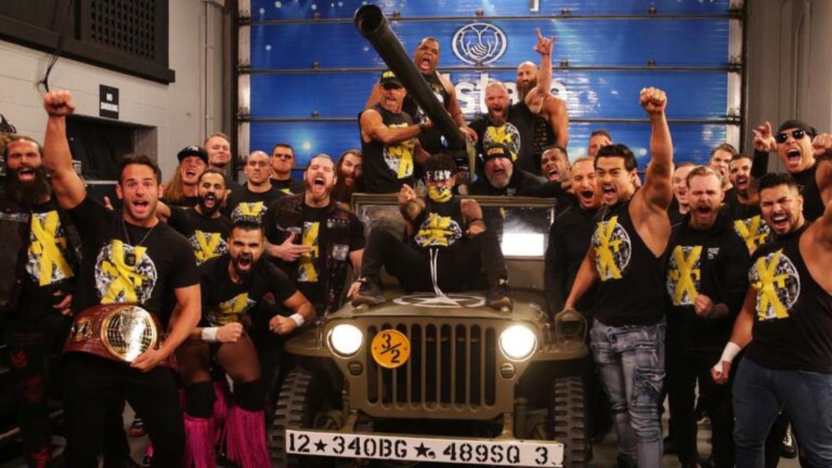 NXT wrestlers standing around and cheering with an army truck in the middle