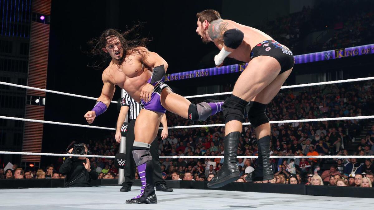 Neville hitting a spin kick on Bad News Barrett, who is doubled over in pain