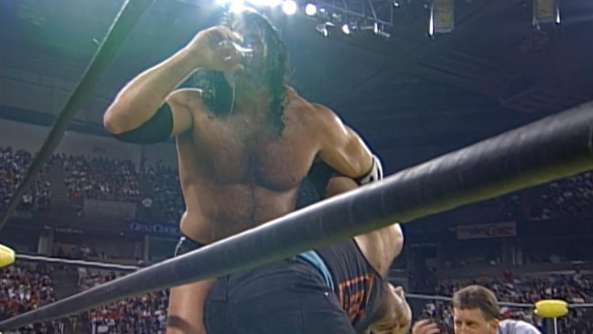 Scott Hall drinking while he has Konnan in an abdominal stretch at WCW Fall Brawl 1998
