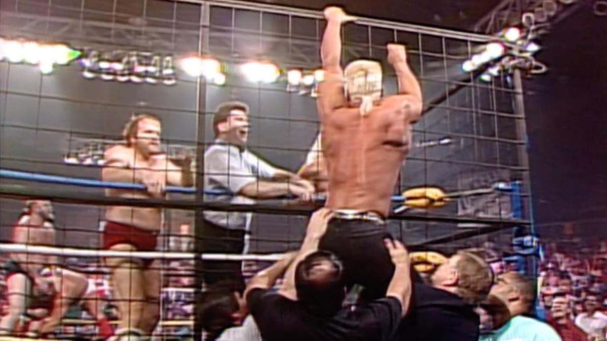 Sting hanging from a cage at Clash of the Champions X as he suffers a torn ACL