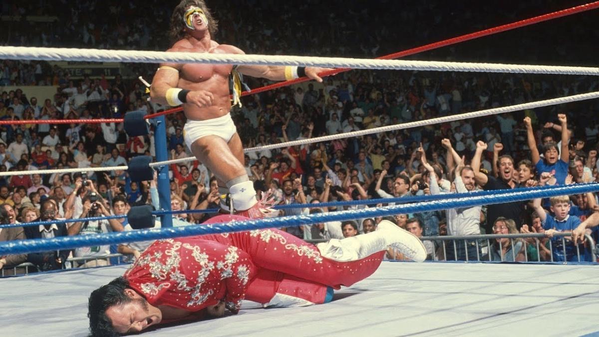 The Honky Tonk Man in pain on the mat as The Ultimate Warrior stands behind him